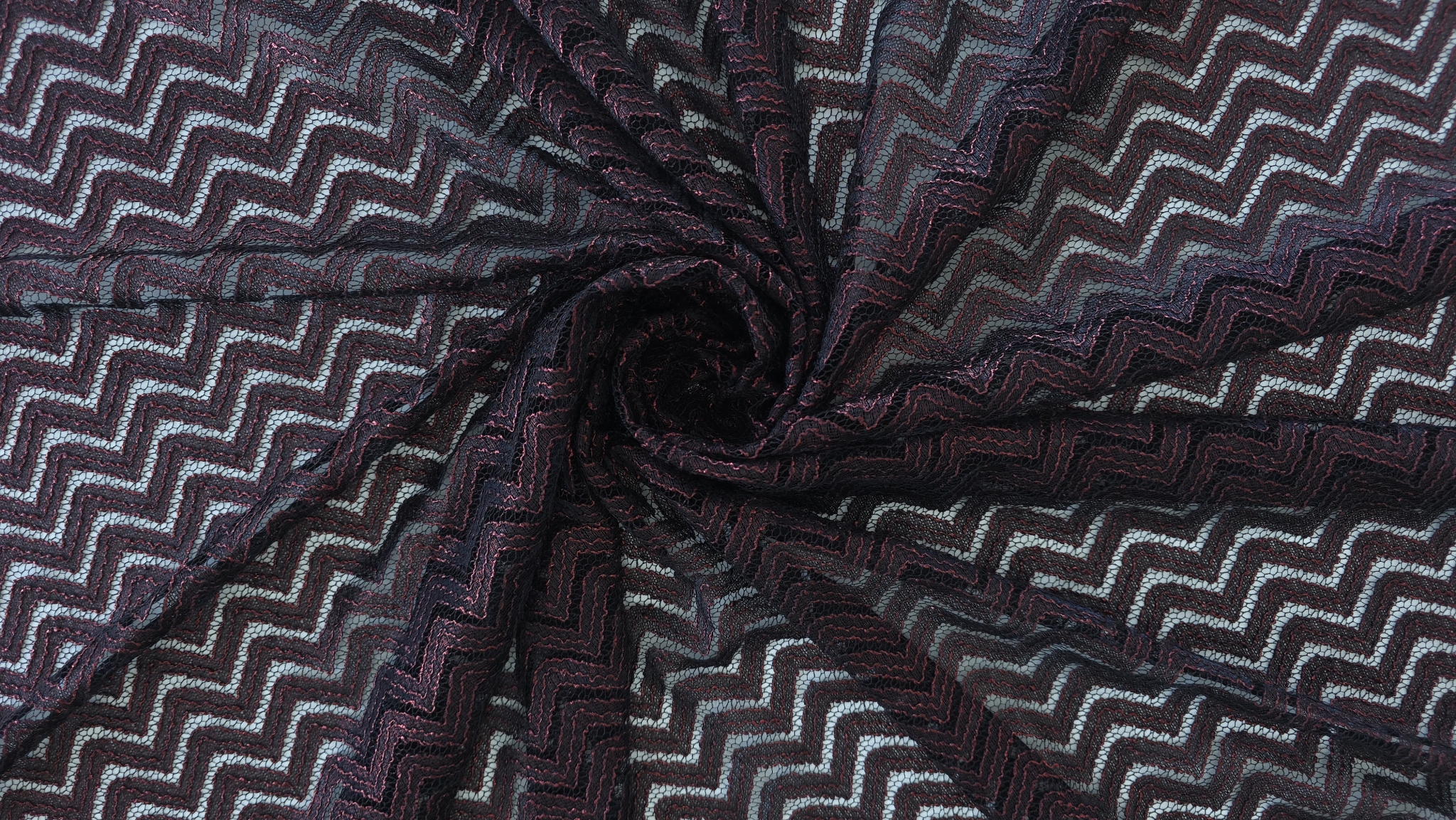 Material răsucit în spirală cu reflexii roșu metalizat pe fond negru