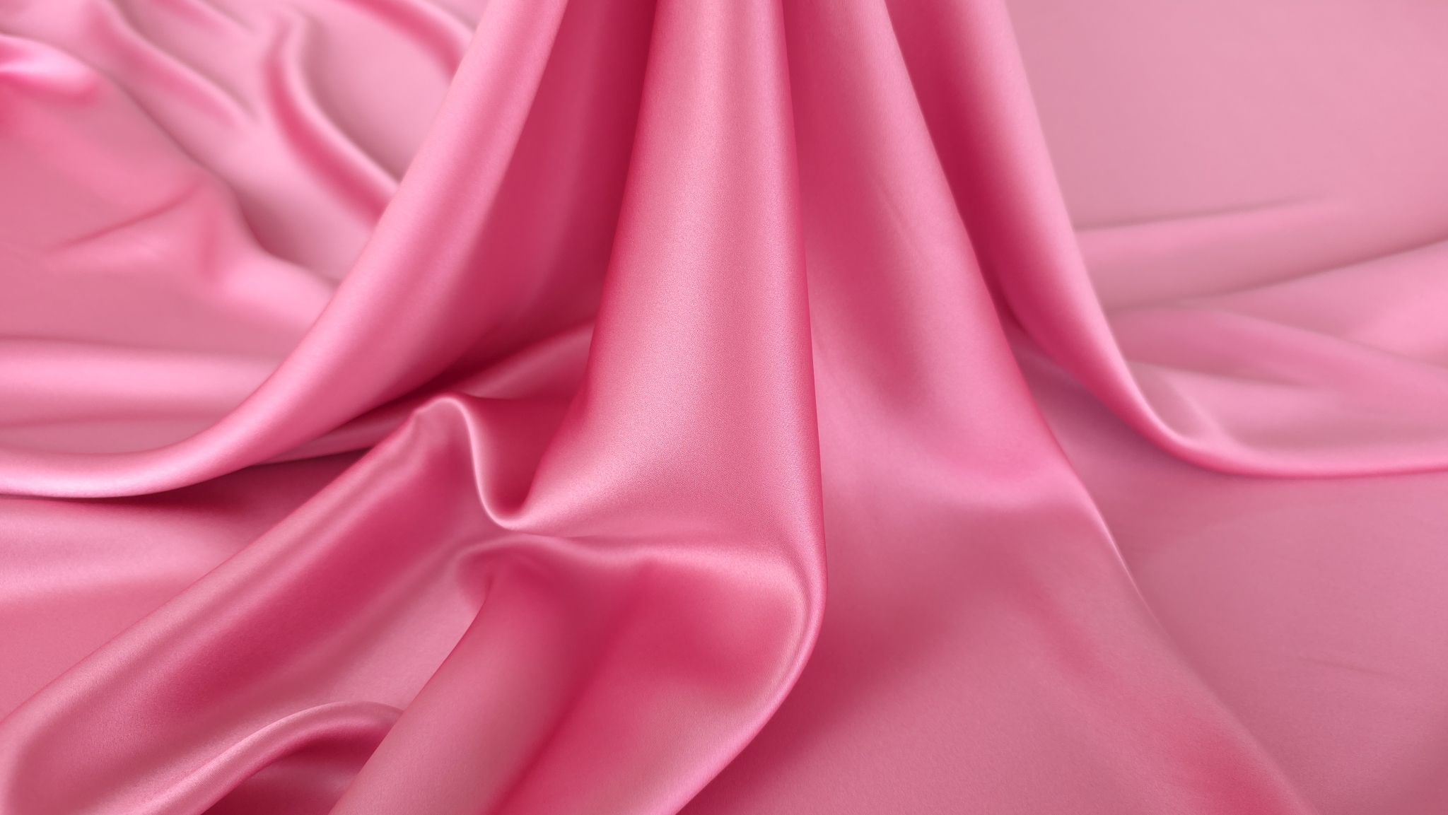 Material satinat roz drapat vertical cu joc de lumină și umbră