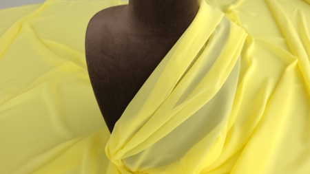 Material vaporos drapat pe bustul manechinului maro cu pliuri diagonale