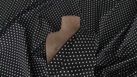 Poplin negru elastic cu buline albe drapat peste manechin maro în prim plan