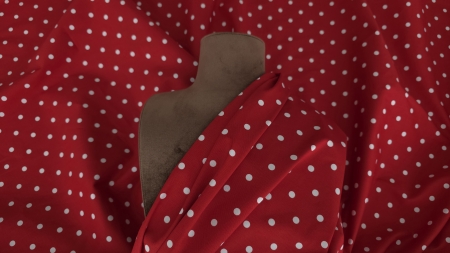 Poplin roșu cu buline albe drapat pe manechin maro, cu falduri moi pe umăr