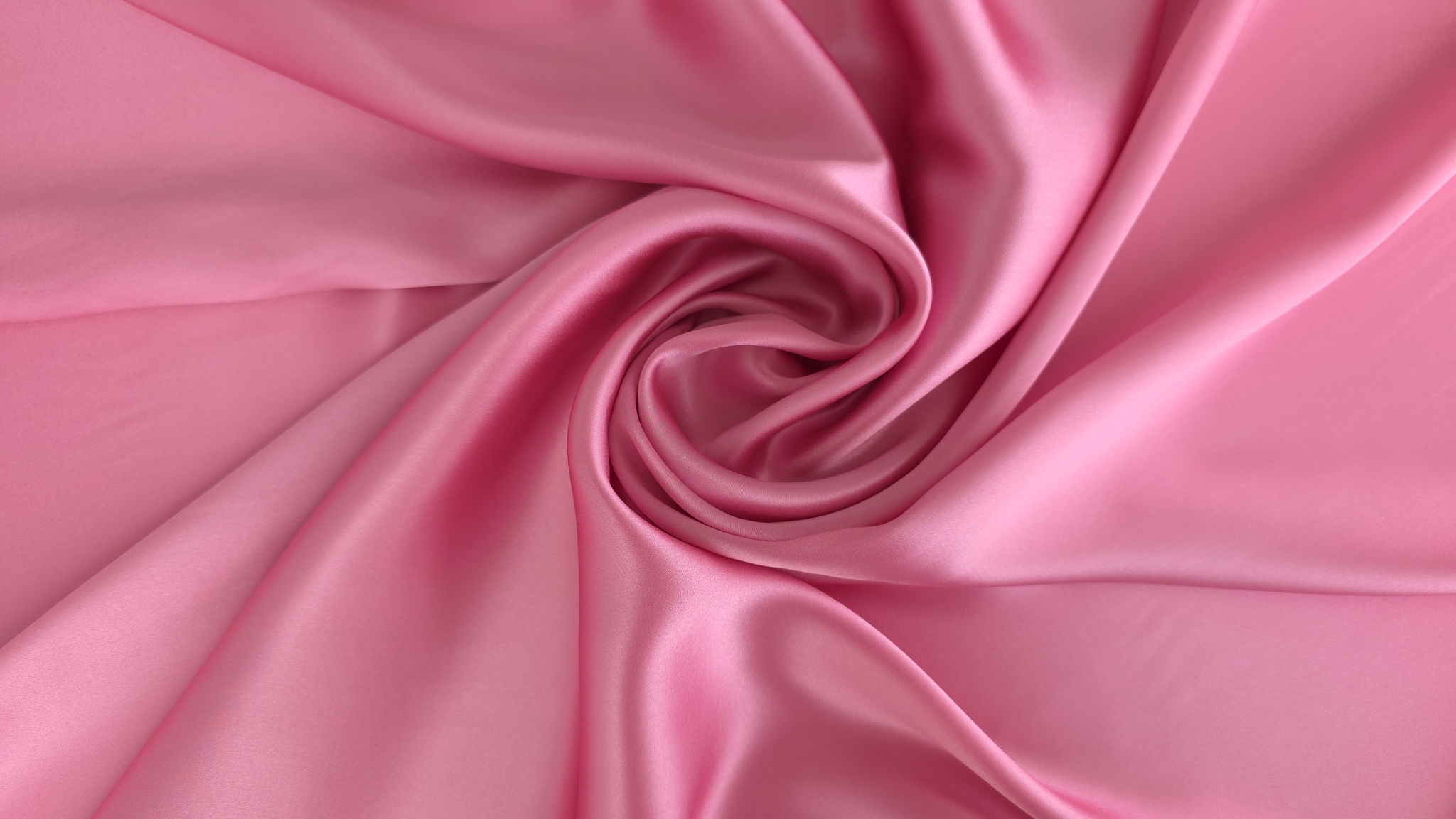 Satin elastic din mătase naturală roz aranjat în spirală pe fundal deschis