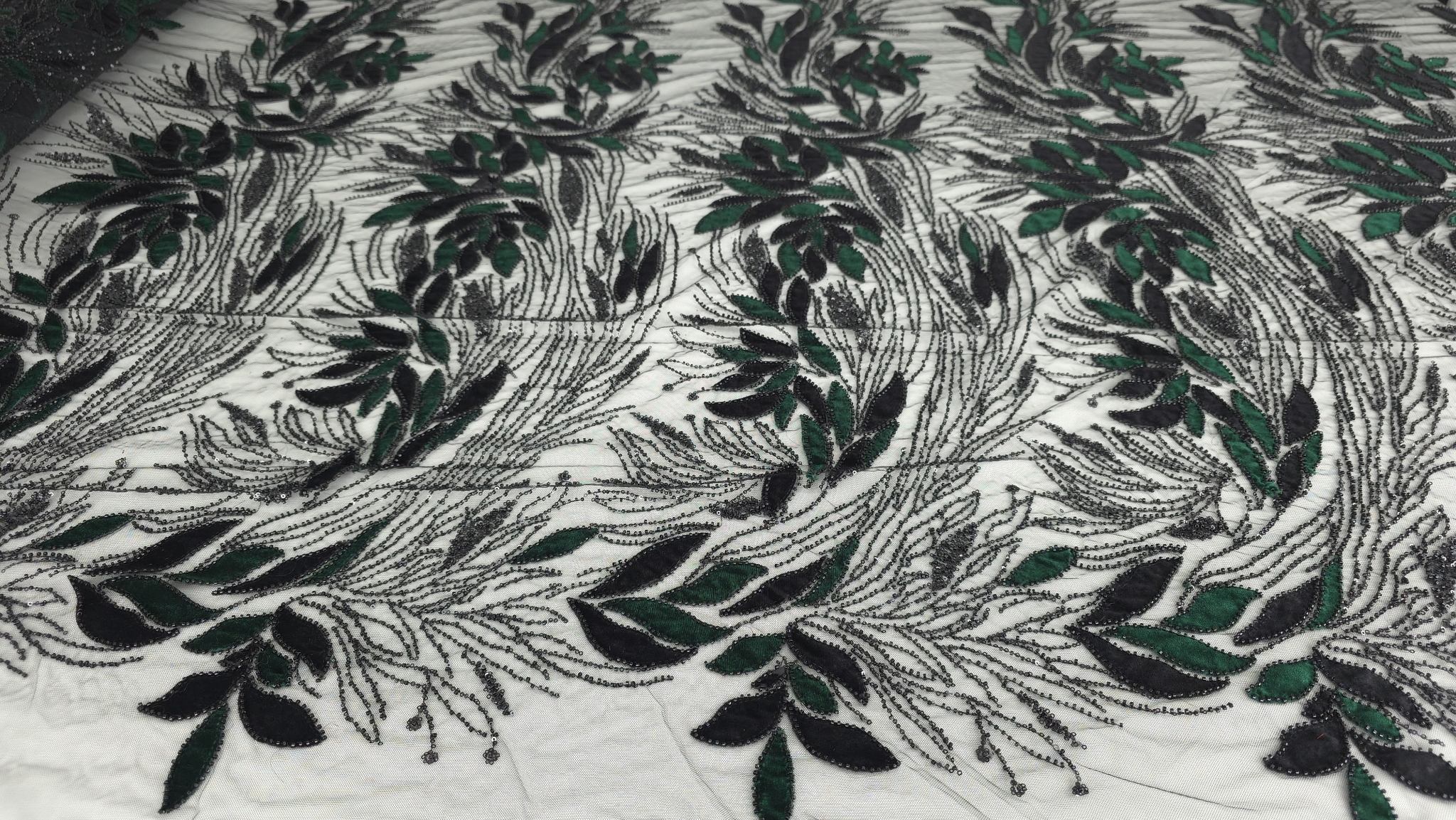 Suprafață brodată cu frunze din catifea neagră și verde pe tulle transparent