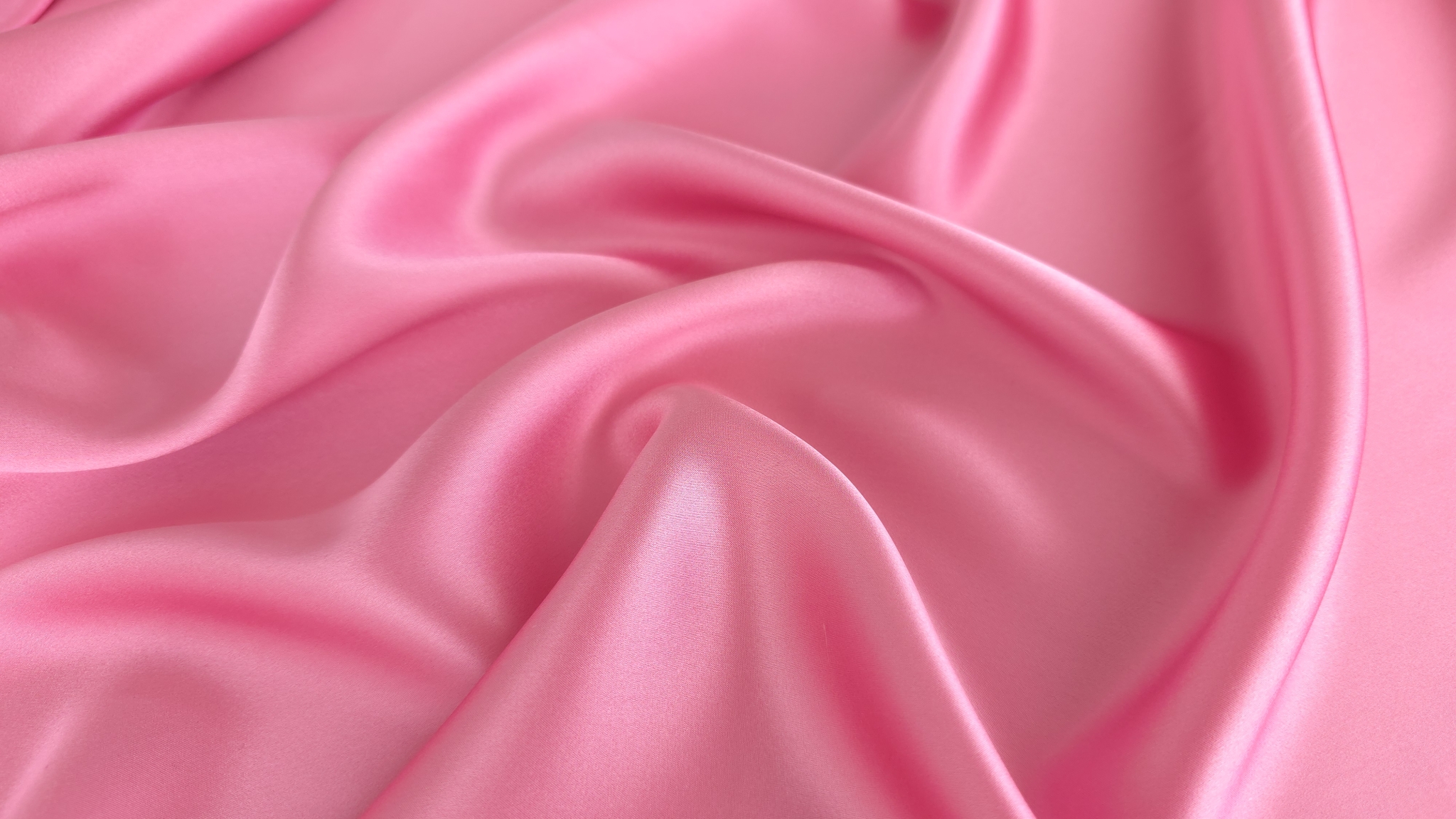 Suprafață netedă și lucioasă de material satinat roz cu reflexii de lumină