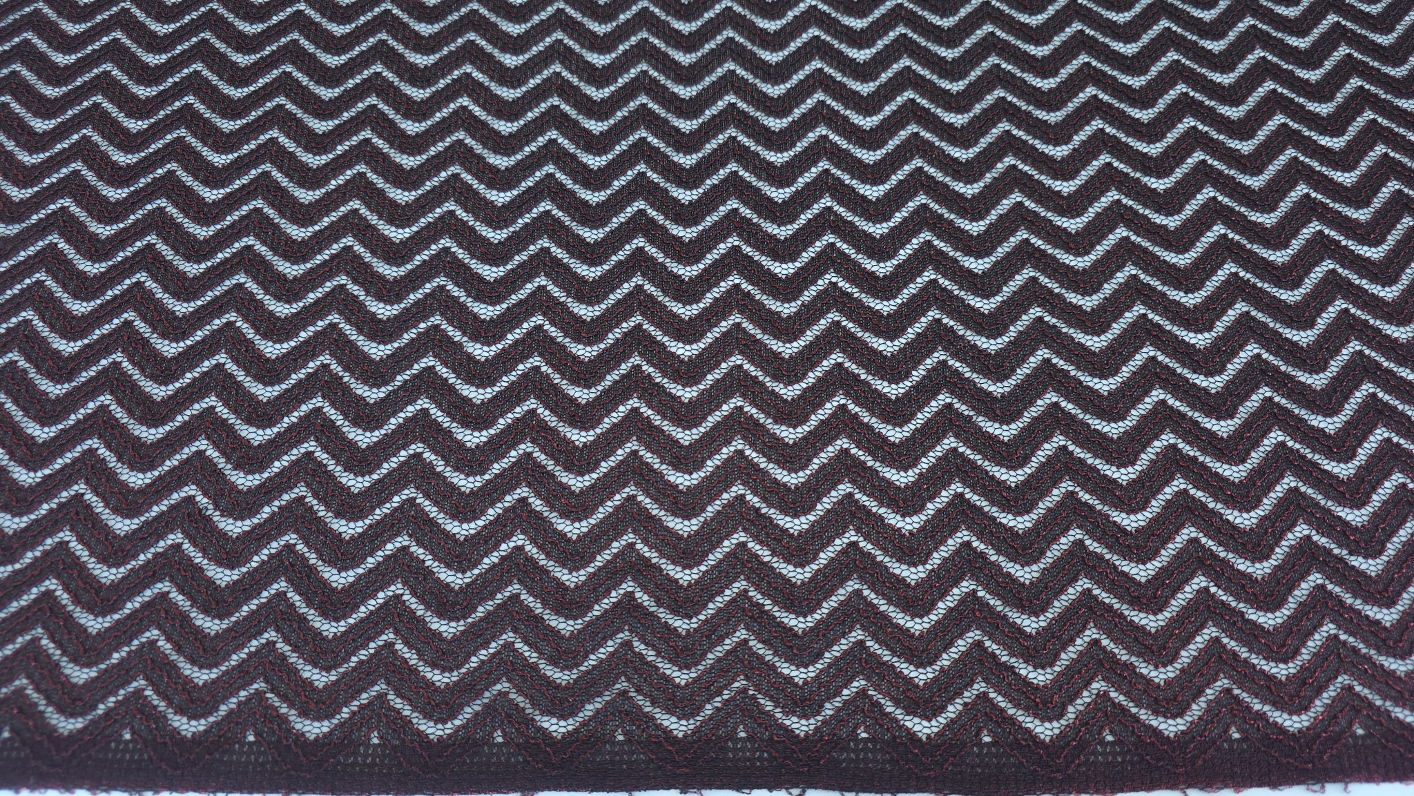 Suprafață uniformă a materialului cu pattern zigzag regulat negru și roșu