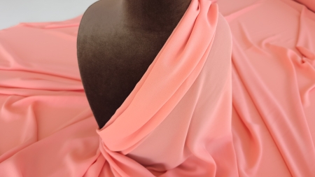 Țesătură triplu voal nuanță piersica drapată pe bust de manechin maro cu prindere diagonală