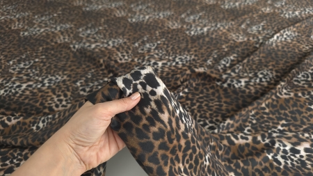 Țesătură vascoza cu elastan animal print ținută în mână, evidențiind flexibilitatea materialului