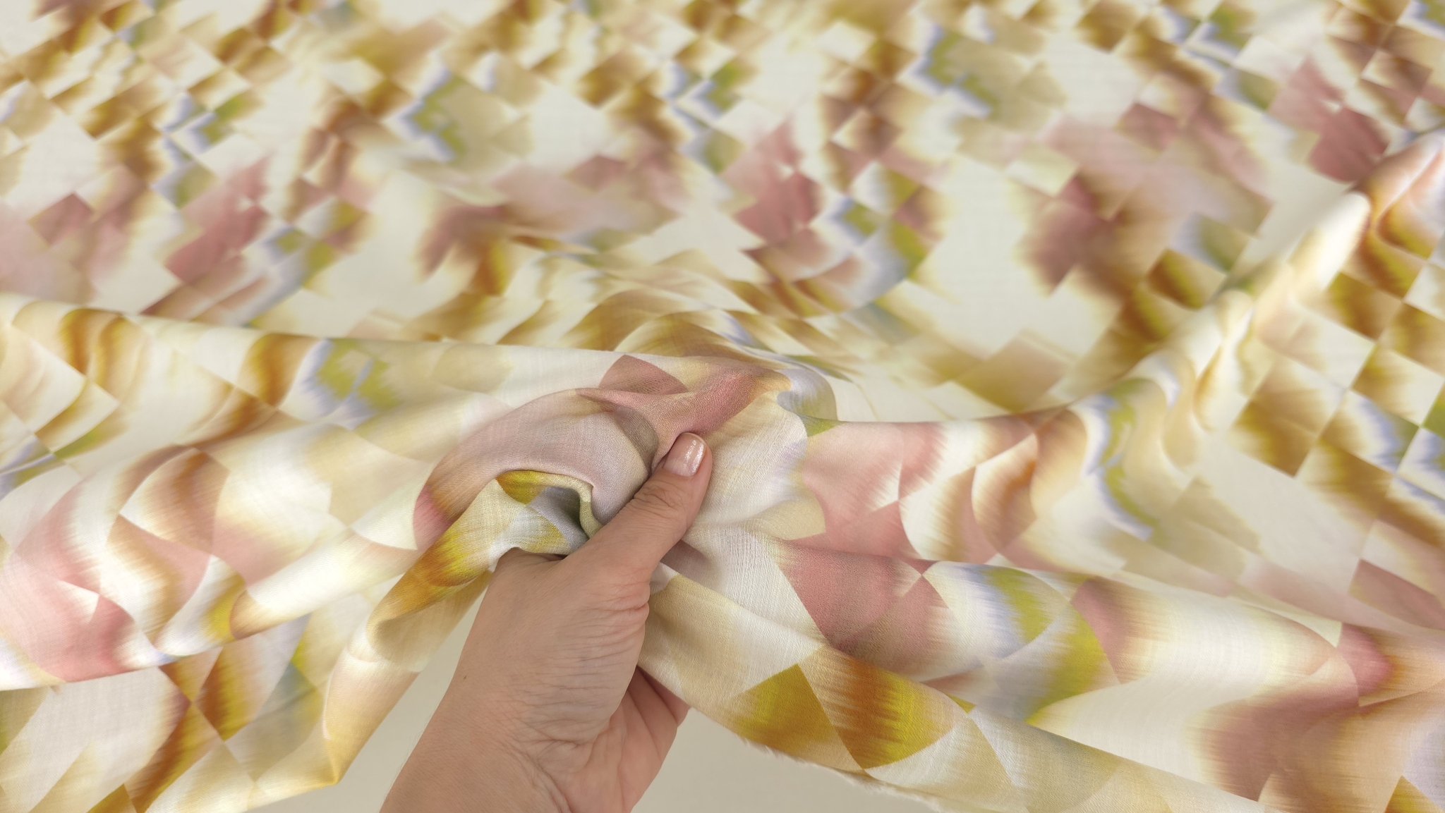 Țesătură vascoza print geometric strânsă în mână evidențiind fluiditatea materialului