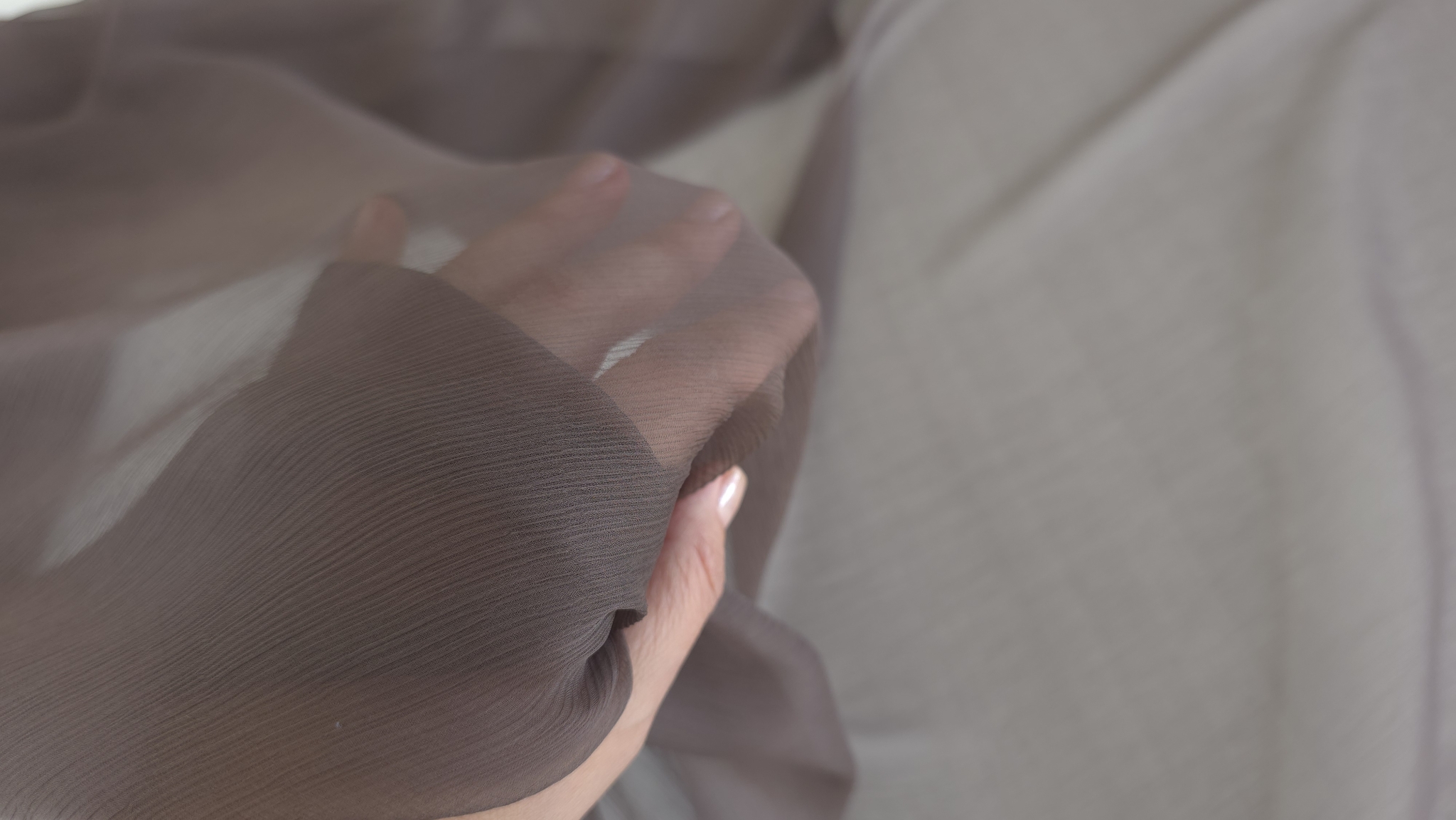 Transparența materialului mocha mousse prin care se vede mâna în plan apropiat