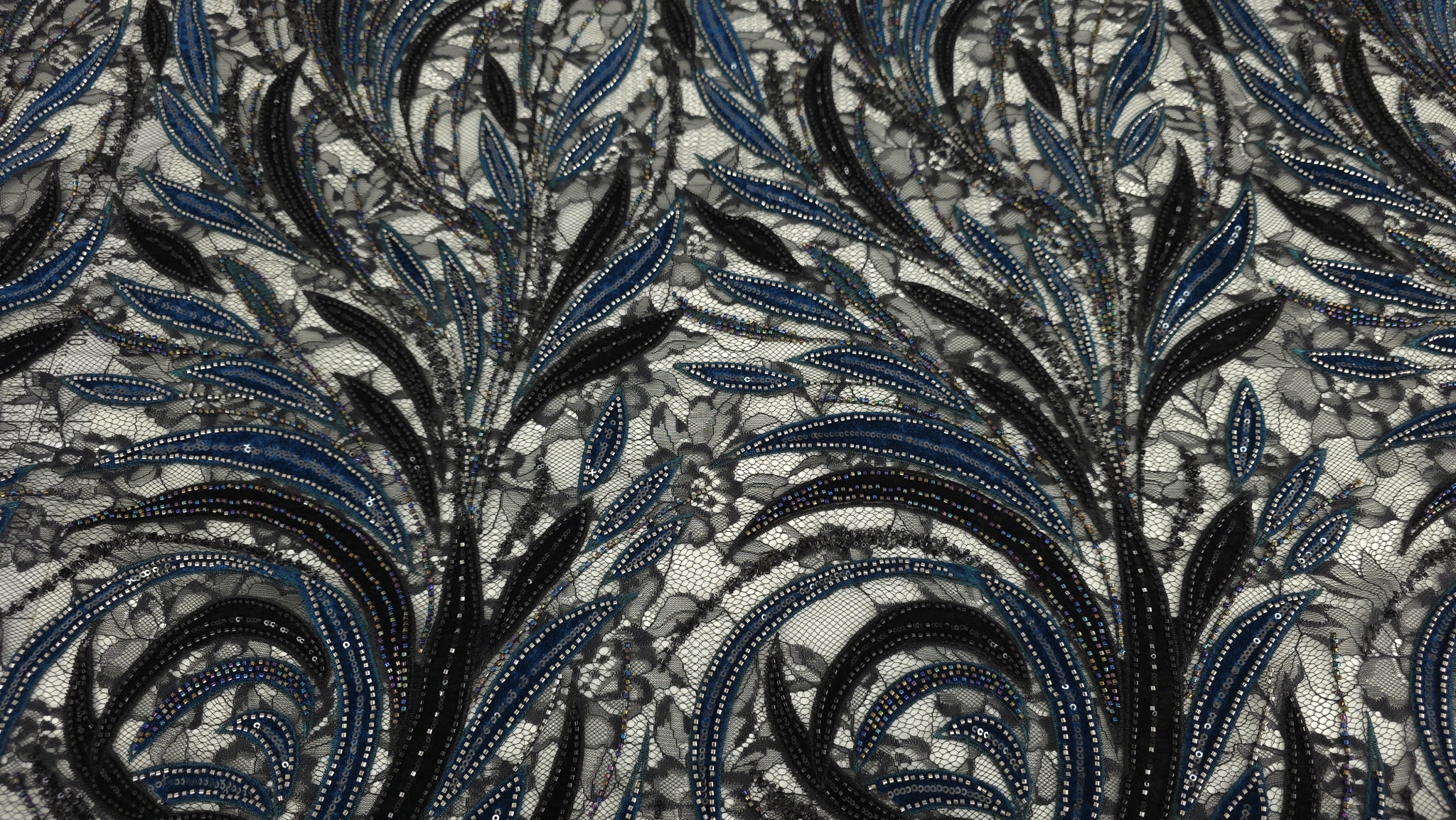 Tulle negru cu desen floral chantilly vizibil între frunzele rare de catifea