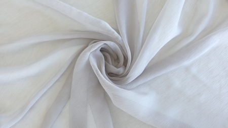 Voal creponat gri nisipiu Muselina din mătase naturală aranjat în spirală pe fundal deschis