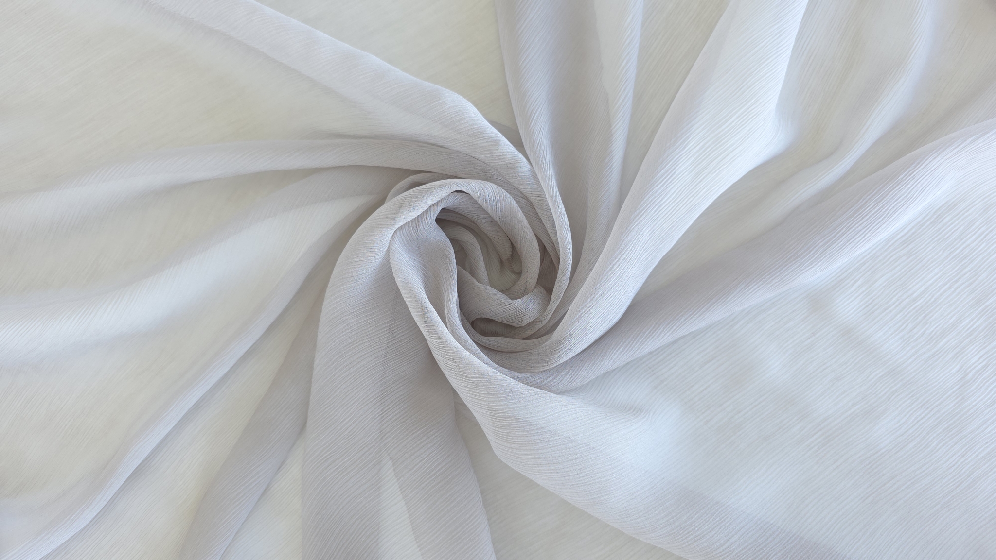 Voal creponat gri nisipiu Muselina din mătase naturală aranjat în spirală pe fundal deschis