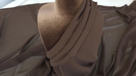 Voal creponat maron ciocolata drapat pe bust de manechin maro cu prindere oblică