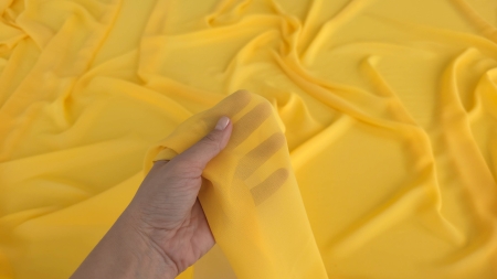 Voal diafan galben soare ridicat în mână cu marginea tăiată vizibilă