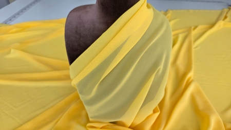 Voal georgette galben soare drapat pe bustul manechinului cu pliuri diagonale pe umăr