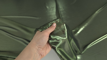 Țesătură verde ținută în mână, evidențiind textura fină și strălucirea peliculei