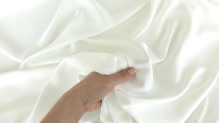 Satin Hugo ivory răsfrânt în mână, ambele fețe satinate vizibile