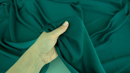 Satin dublu față verde pădure ținut în mână, falduri ample în lumină naturală