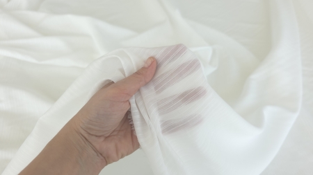 mână strângând țesătură ivory dungată transparența dungilor vizibilă prin straturi