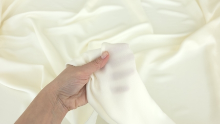 metraj satin ivory intens din mătase și acetat strâns în mână cu falduri relaxate în fundal