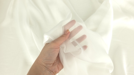 Mână acoperită cu voal transparent ivory, grad ridicat de transparență vizibil prin strat