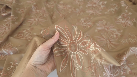 Material caffe latte tinut in mana, transparenta subtila vizibila la capatul pliat, falduri fluide fine