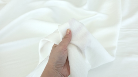 Material ivory ținut în mână, falduri ample și line, grosime medie vizibilă