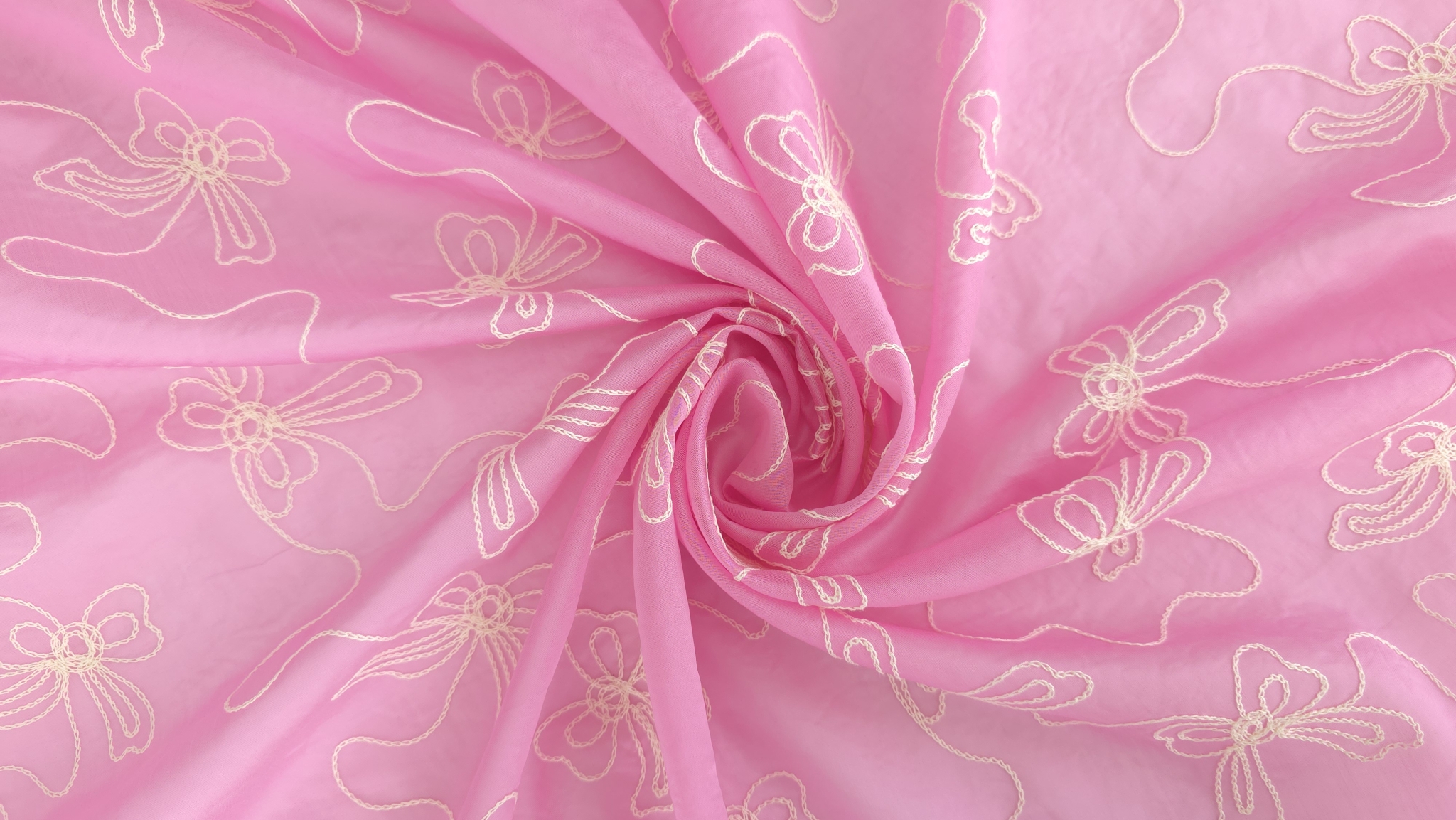 Tesatura roz rasucita in forma de trandafir, fire broderie ivory vizibile in spirala, unghi de sus