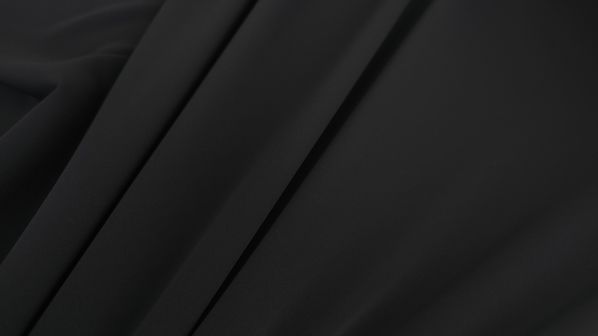 falduri diagonale material negru opac suprafata fina prim plan