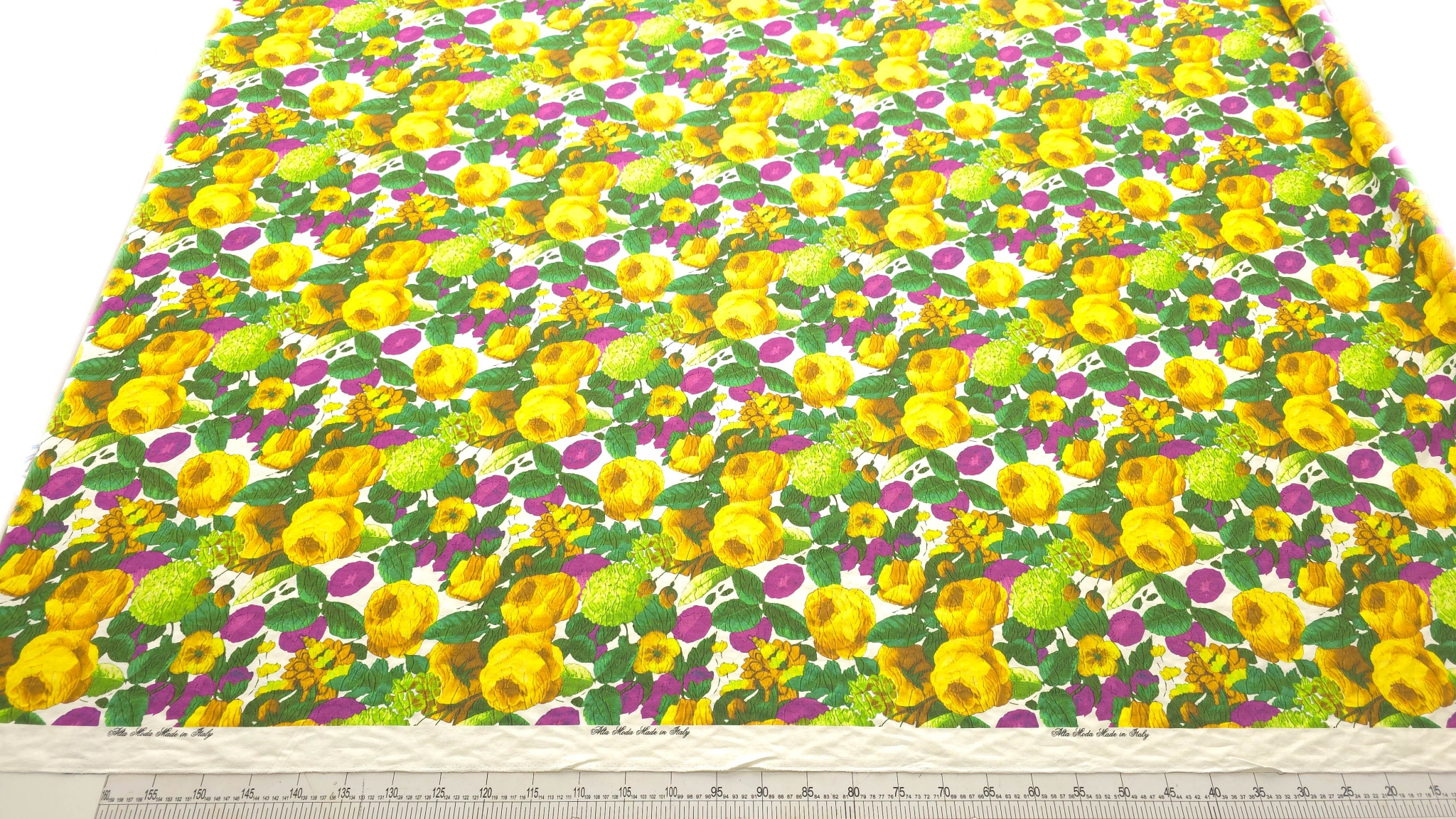 Brocard cu imprimeu floral din bumbac verde mov galben cod PCS127 EV34 întins pe masă lângă riglă
