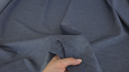 Denim jeans bleumarin la metru strans in mana peste suprafata sifonata