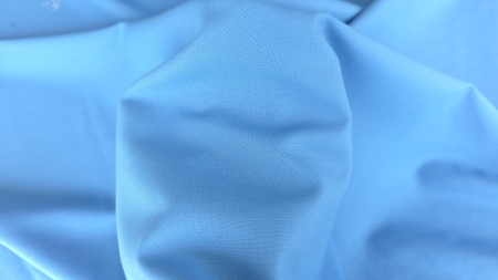 Material bleu ținut în mână cu falduri moi