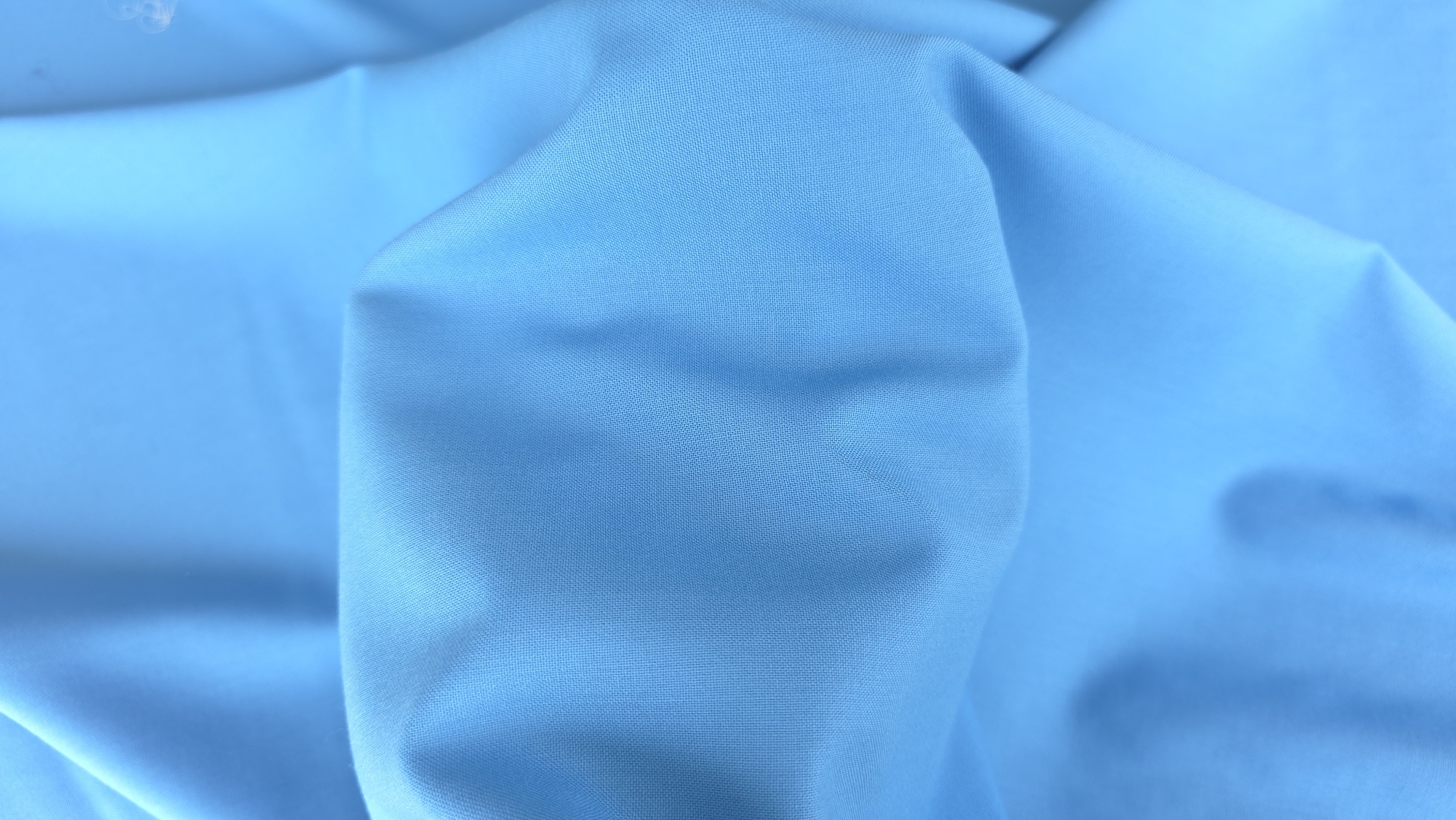Material bleu ținut în mână cu falduri moi