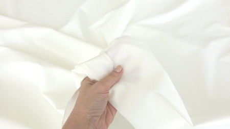 Poplin ivory gros din bumbac si elastan ținut în mână evidențiind finisajul fin al materialului