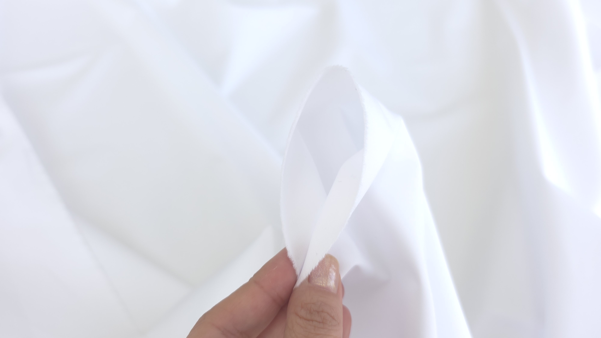material alb tinut intre degete cu marginea vizibila