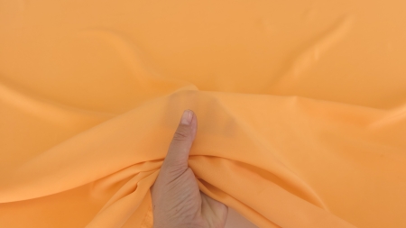 material portocaliu pus pe mână în lumină naturală