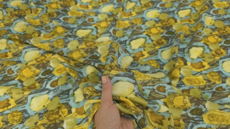 material pus pe mână cu formele turcoaz galben și maro în lumină naturală