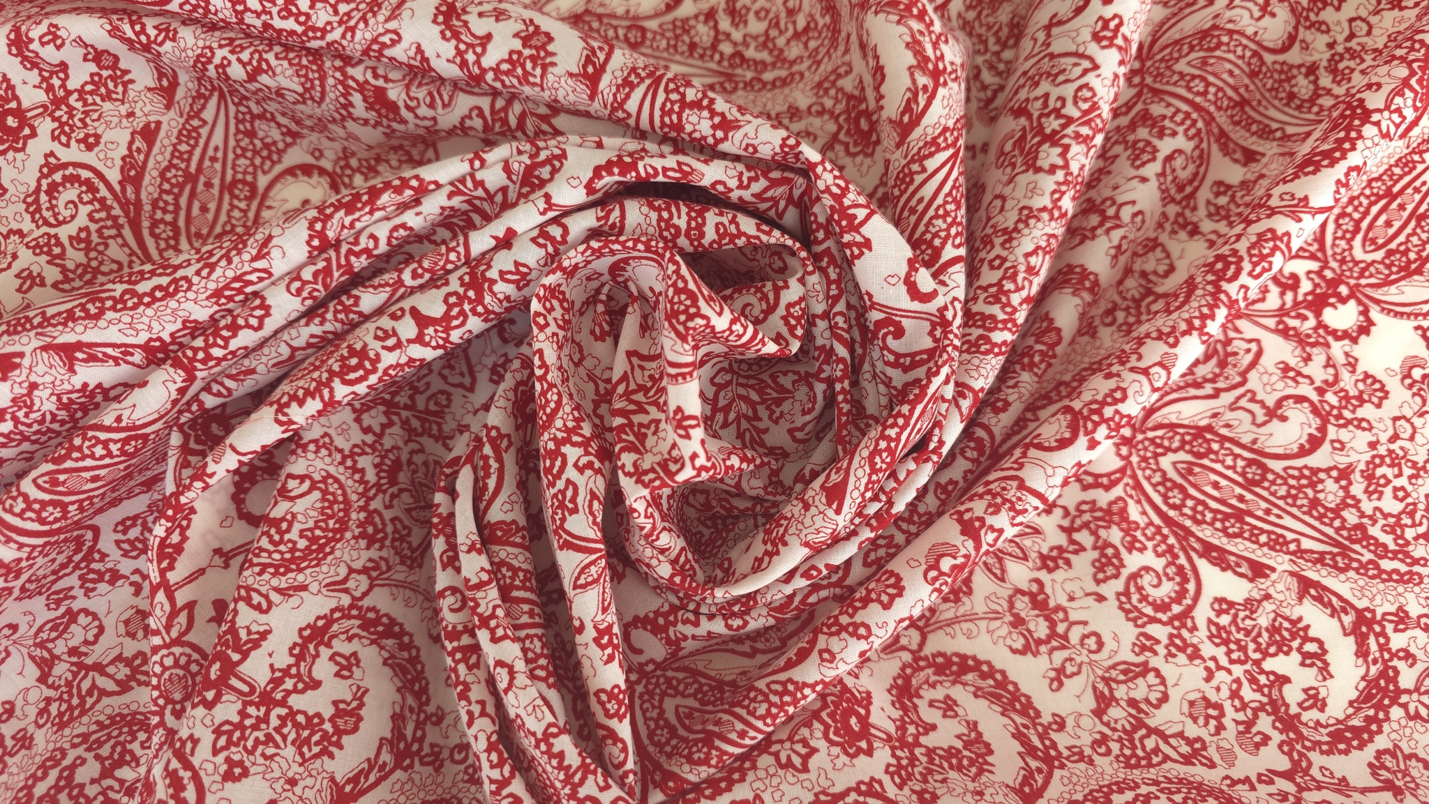 material rasucit in spirala cu imprimeu rosu ornamental pe fond alb