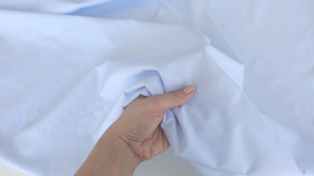 poplin cu linii bleu la metru ținut în mână cu falduri