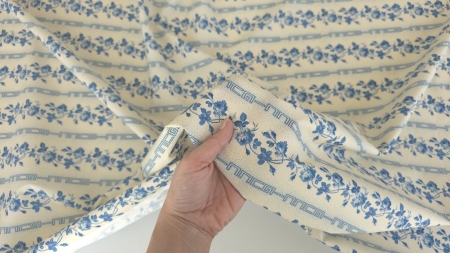 poplin floral albastru la metru ținut în mână cu cute moi