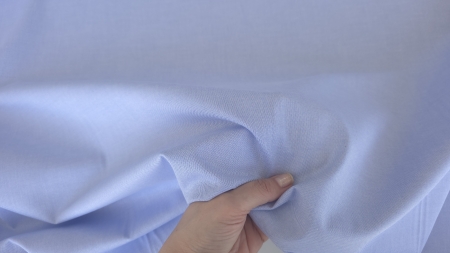 poplin gros tip denim din bumbac si elastan bleu tinut in mana