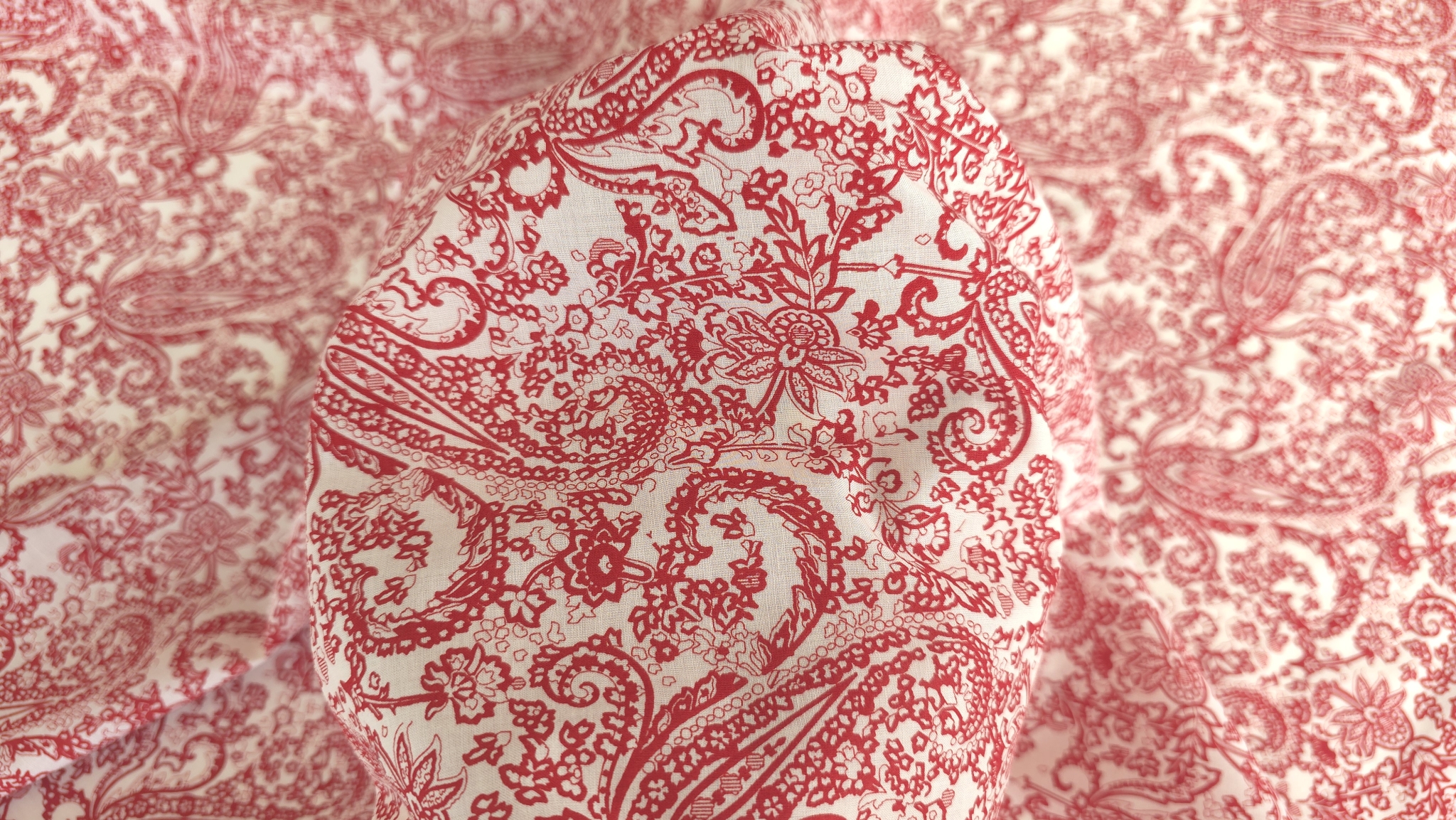 prim plan cu desen paisley rosu dens si elemente florale mici pe crem