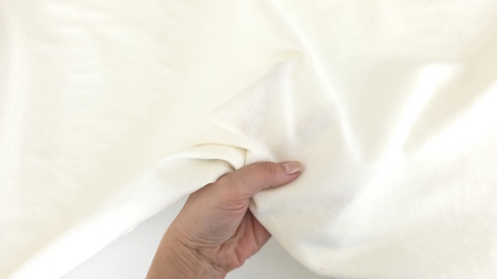 tesatura elastica cu in si bumbac ivoire prinsa in mana cu falduri