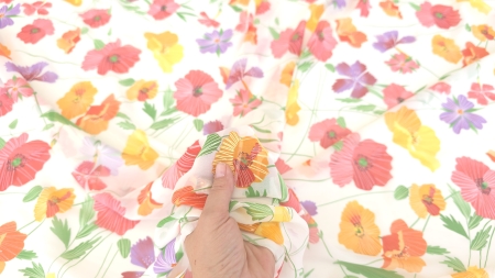Material floral multicolor ridicat în mână care arată suplețea țesăturii