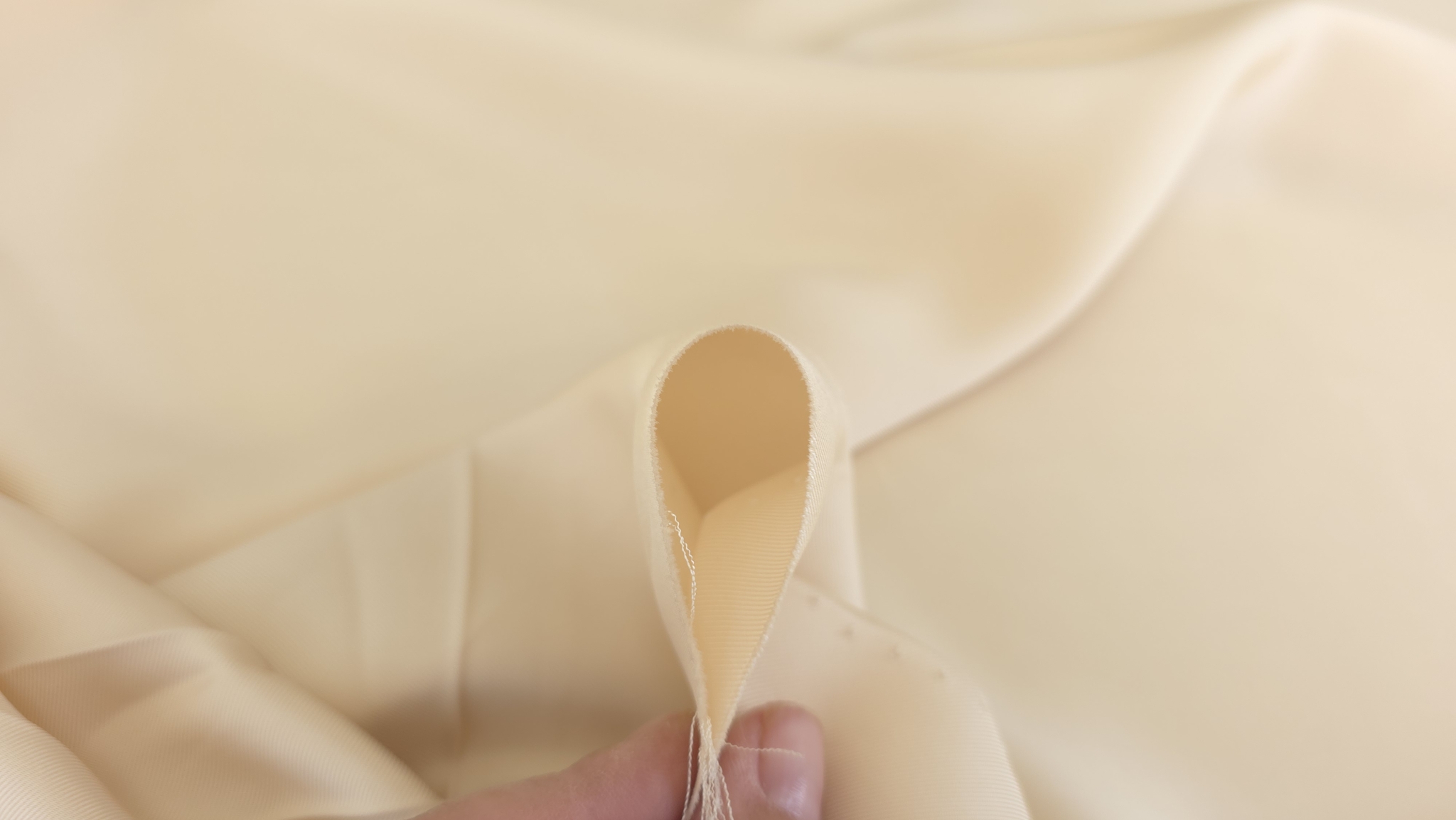 Material twill crem cu diagonala fina prins intre degete la margine