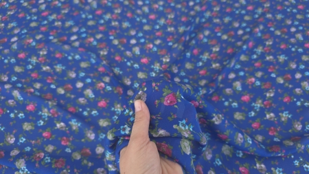 Tesatura albastra cu buchete florale multicolore tinuta in mana