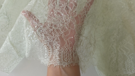 bucata de material dantelat tinuta pe palma cu floare mare brodata