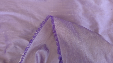 Shantung satinat mov lavanda colt intors cu margine destramata pe fundal lila