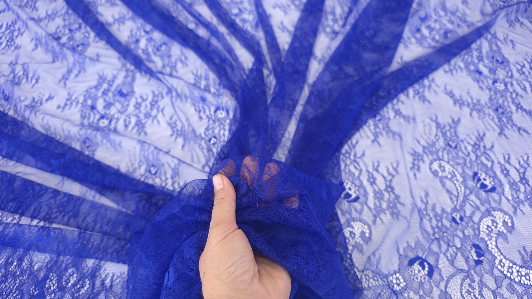 Dantelă Chantilly albastru regal ținută în mână, cu flori și zone transparente