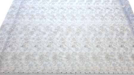 Dantelă brodată floral pe organza albă întinsă pe masă lângă riglă gradată